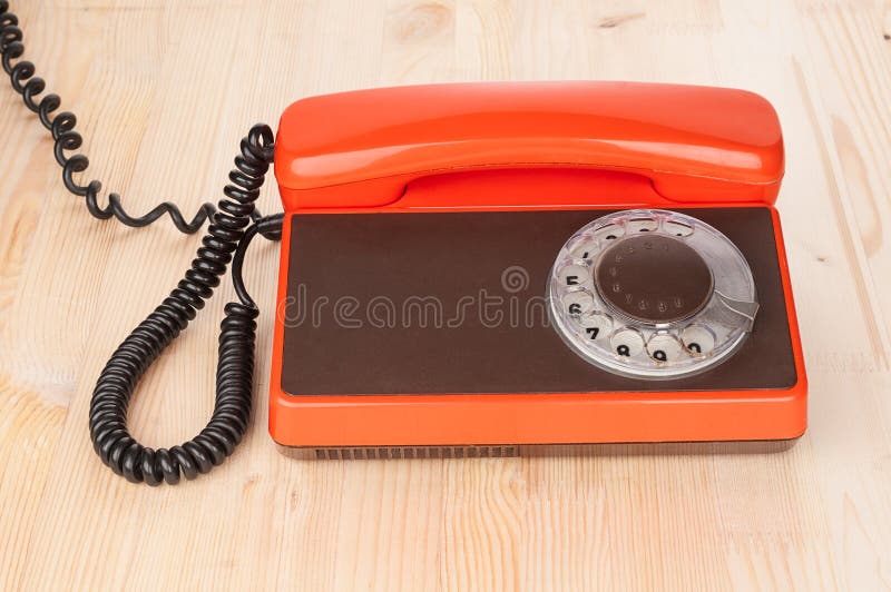 Teléfono antiguo anaranjado en el escritorio de madera fotos de archivo libres de regalías Teléfono antiguo anaranjado en el escritorio de madera fotos de archivo libres de regalías