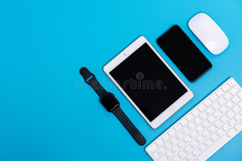 Teléfono elegante, reloj elegante, tableta, ratón y teclado en fondo del azul de cielo fotografía de archivo Teléfono elegante, reloj elegante, tableta, ratón y teclado en fondo del azul de cielo fotografía de archivo