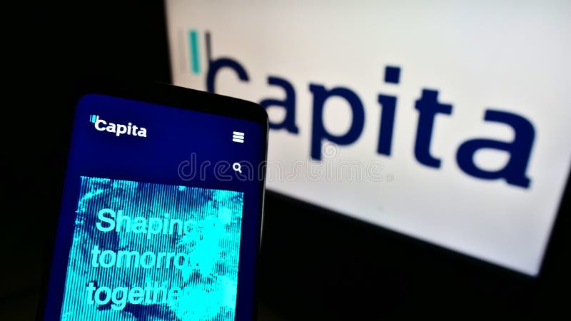 Teléfono móvil con sitio web de la empresa británica de externalización de procesos, per cápita plc en pantalla frente al logotipo imágenes de archivo libres de regalías