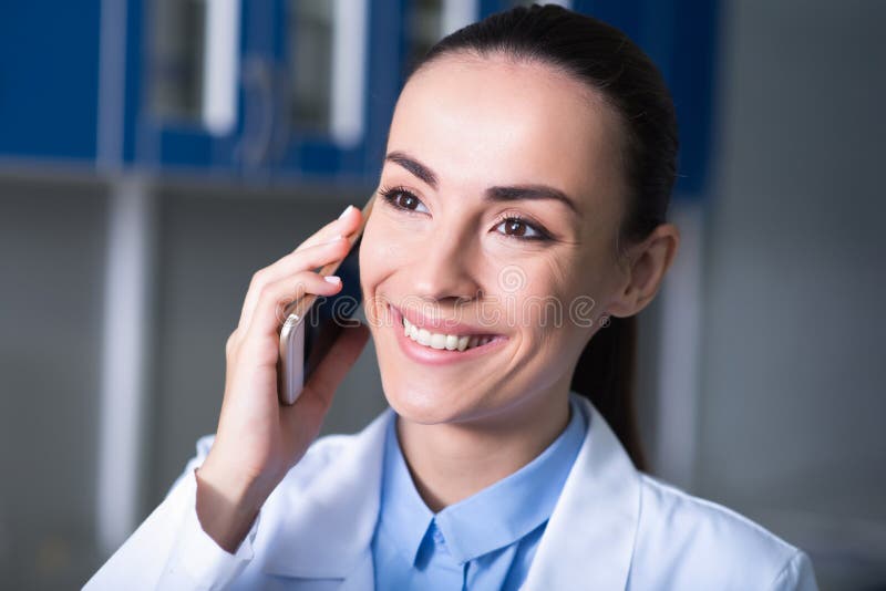 Teléfono móvil de custodia experto agradable lindo cerca de su cabeza y sonrisa imágenes de archivo libres de regalías Teléfono móvil de custodia experto agradable lindo cerca de su cabeza y sonrisa imágenes de archivo libres de regalías