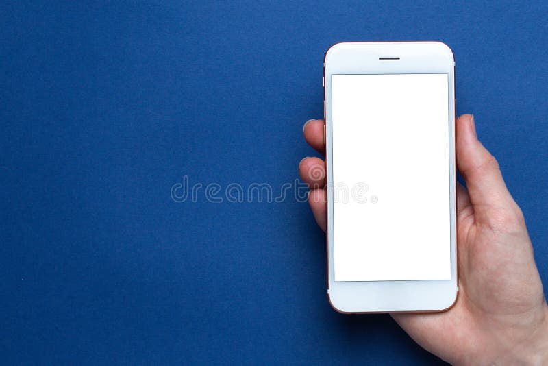 Mobile phone in hand on a classic blue background with copyspace top view. Trendy Pantone color 2020. Mobile phone in hand on a classic blue background with copyspace top view. Trendy Pantone color 2020