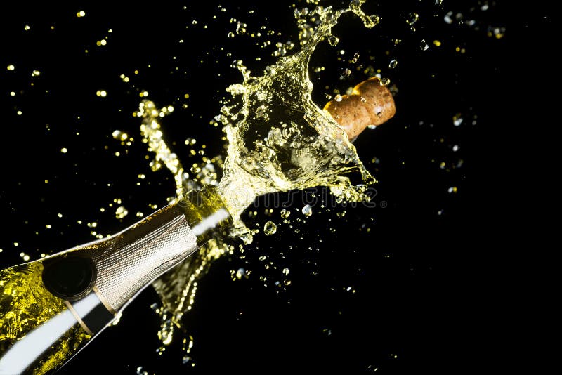 Tema da celebração com explosão de espirrar o vinho espumante do champanhe no fundo preto foto de stock Tema da celebração com explosão de espirrar o vinho espumante do champanhe no fundo preto foto de stock