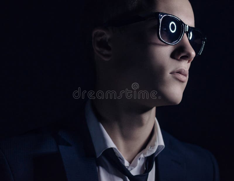 Tema del modo degli uomini: giovane bello in vestito alla moda ed occhiali da sole che stanno su un fondo scuro nello studio fotografie stock libere da diritti Tema del modo degli uomini: giovane bello in vestito alla moda ed occhiali da sole che stanno su un fondo scuro nello studio fotografie stock libere da diritti