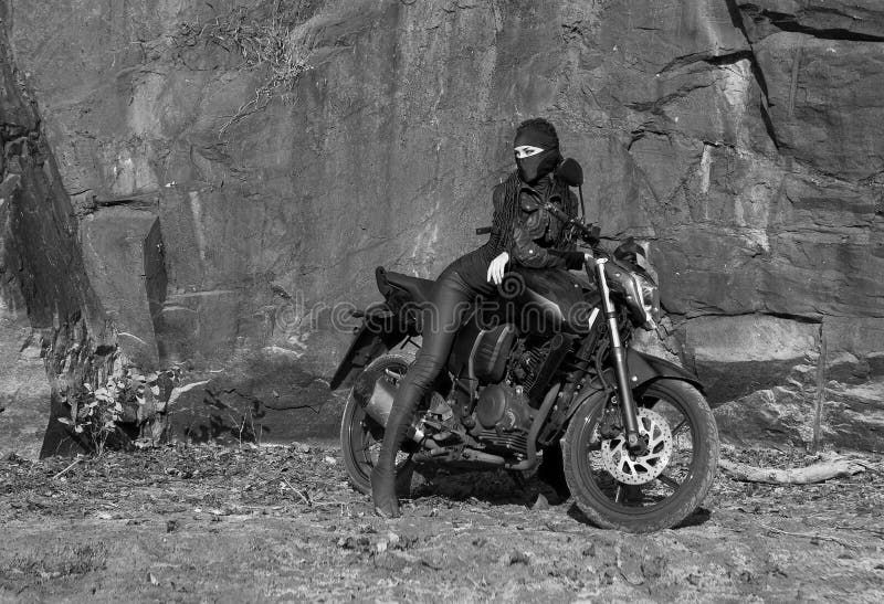 Tema del motorista: mujer atractiva hermosa con la máscara que presenta con el motorbik fotografía de archivo libre de regalías Tema del motorista: mujer atractiva hermosa con la máscara que presenta con el motorbik fotografía de archivo libre de regalías