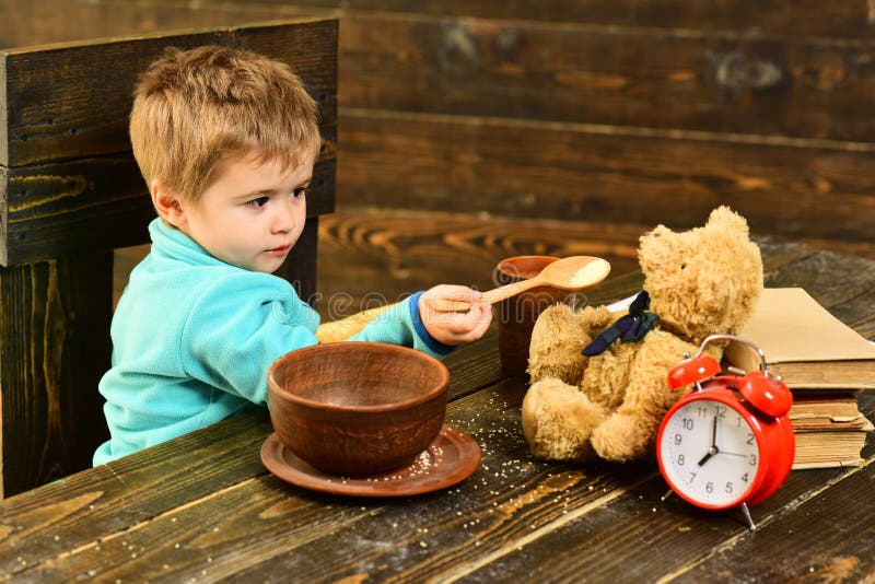 Tempo di pranzo Il ragazzino e l'orsacchiotto cenano insieme Giocattolo dell'alimentazione del bambino con la cena sana Cena con