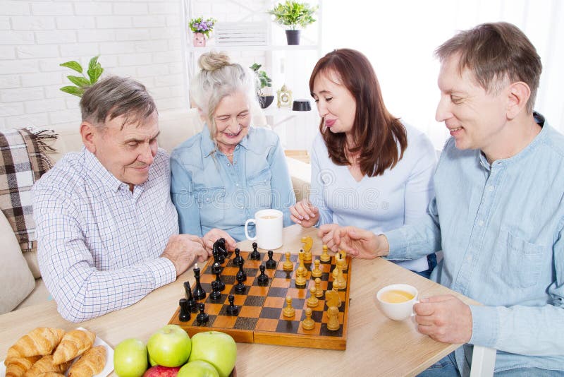 Tempo felice del gioco di scacchi della famiglia alla casa di cura per gli anziani I genitori con i bambini si divertono la conve fotografia stock Tempo felice del gioco di scacchi della famiglia alla casa di cura per gli anziani I genitori con i bambini si divertono la conve fotografia stock