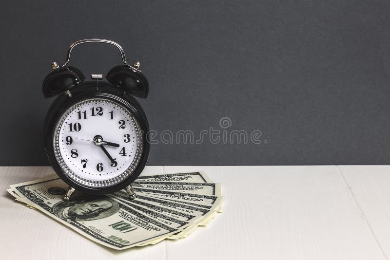 Tempo - i soldi Dollari di contanti Retro sveglia e denaro contante sulla tavola