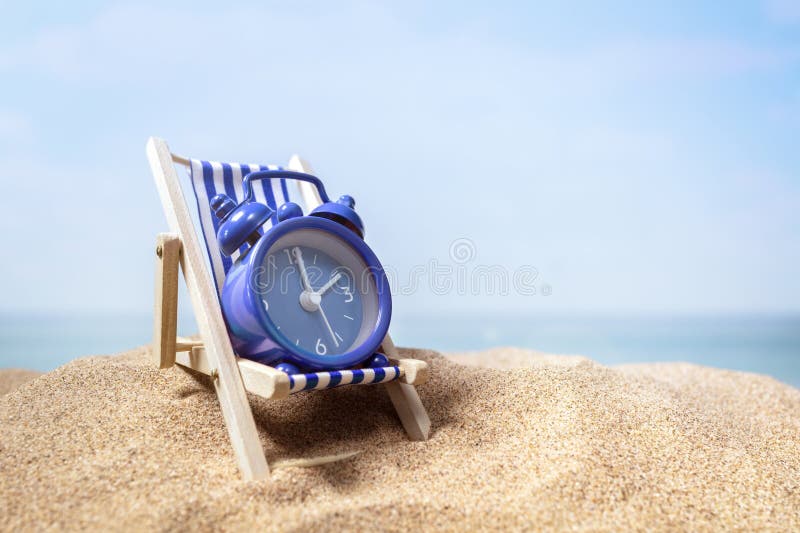 Tempo para relaxar o despertador relaxando na cadeira de baralho na praia imagens de stock