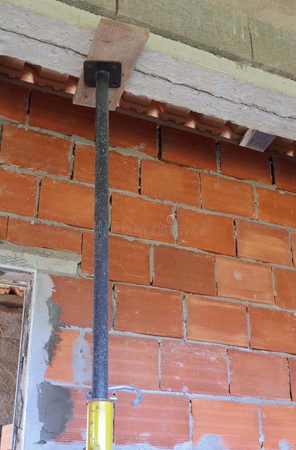 A close-up shot of a construction site showing a temporary support pole holding up a ceiling beam against a brick wall. Load structural stock images, royalty-free photos and pictures