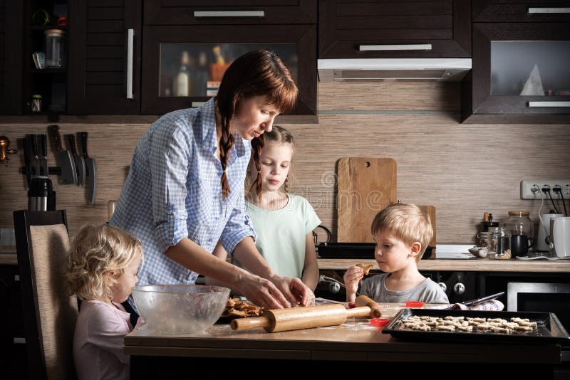 Temps de famille : Maman avec trois enfants préparant des biscuits dans la cuisine Vraie famille authentique image libre de droits Temps de famille : Maman avec trois enfants préparant des biscuits dans la cuisine Vraie famille authentique image libre de droits