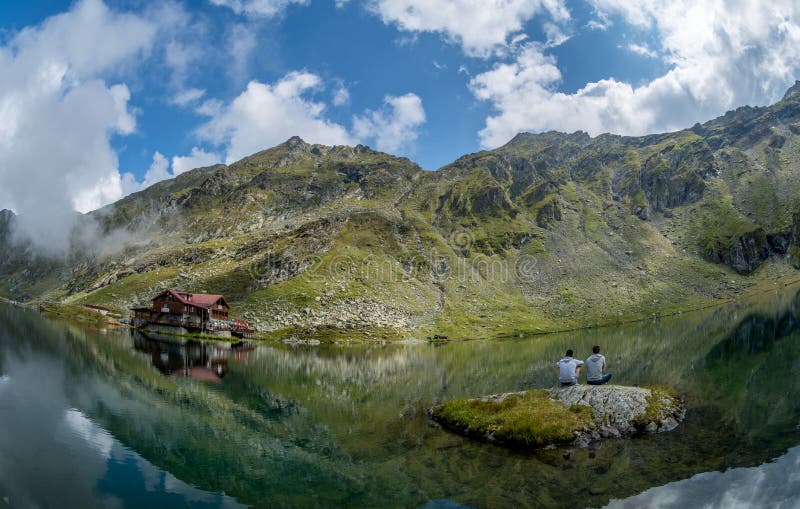 Temps de lac Balea et d'hôtel de Balea au printemps avec des nuages photographie stock Temps de lac Balea et d'hôtel de Balea au printemps avec des nuages photographie stock