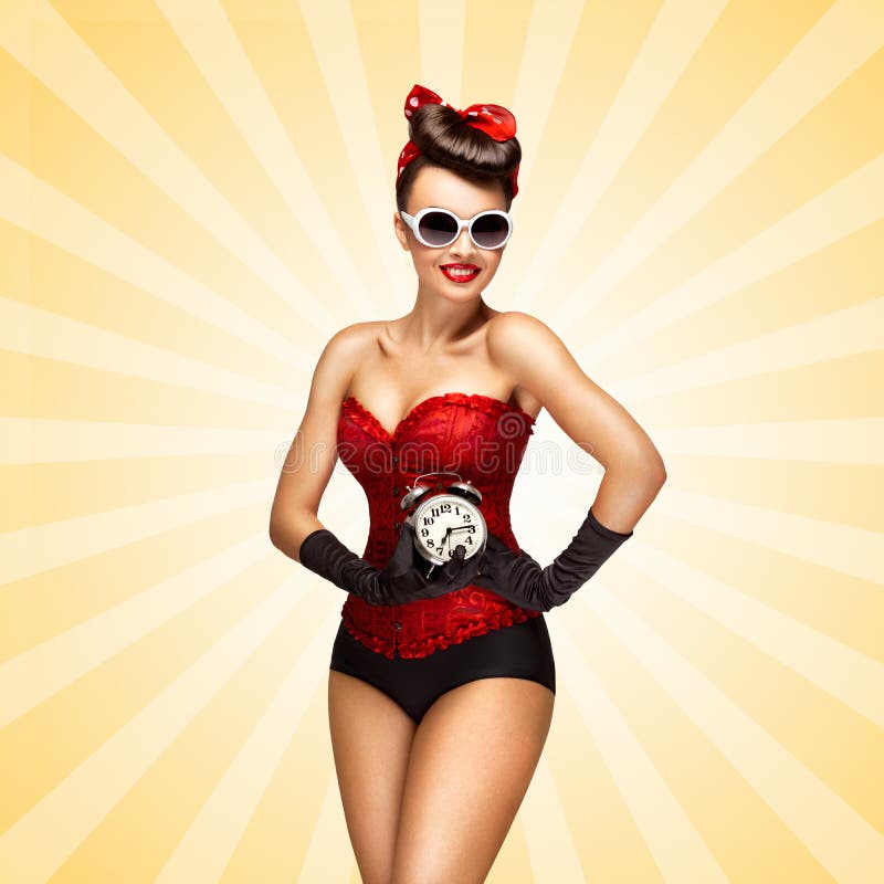 Glamorous pinup girl in a red vintage corset holding a retro alarm clock in her hand and smiling on colorful abstract cartoon style background. Glamorous pinup girl in a red vintage corset holding a retro alarm clock in her hand and smiling on colorful abstract cartoon style background.