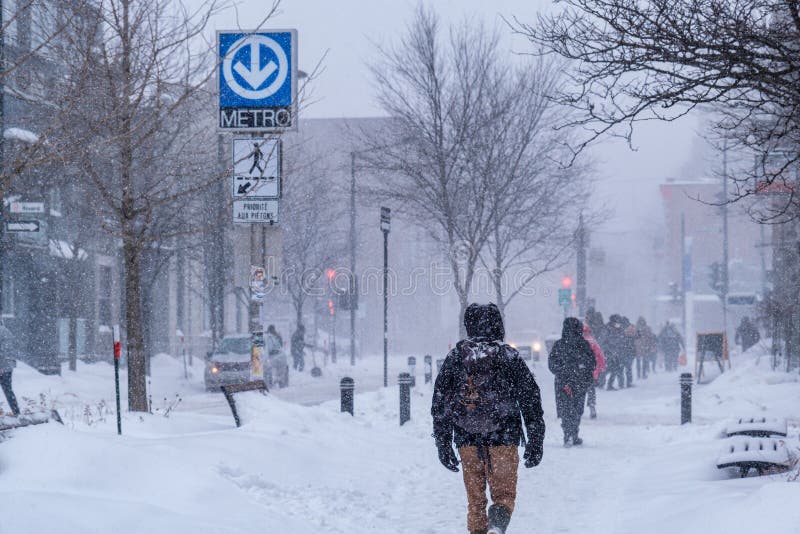 Montreal, CA - 2 February 2021: People walking on the street during heavy snowfall. Montreal, CA - 2 February 2021: People walking on the street during heavy snowfall