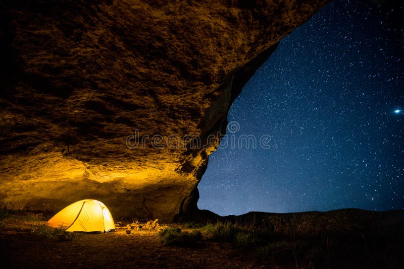 Tenda di campeggio d'ardore nella grotta di notte sotto un cielo stellato fotografie stock Tenda di campeggio d'ardore nella grotta di notte sotto un cielo stellato fotografie stock
