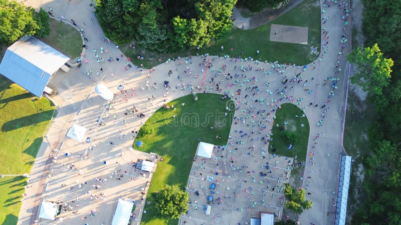 Tendas de quadros e pavilhão do parque local com corredores lotados alinham-se antes da linha de início da corrida comunitária fotos de stock