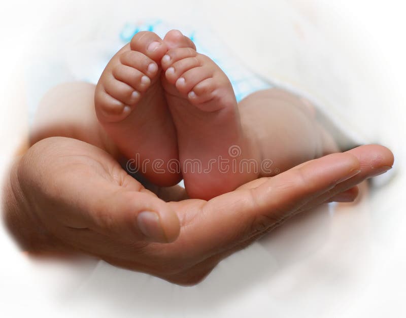 Close up of a father's hand cradling babies feet. Close up of a father's hand cradling babies feet