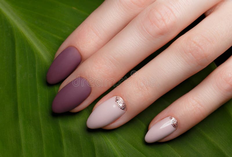 Tender neat manicure on female hands on green leaves background. Nail design