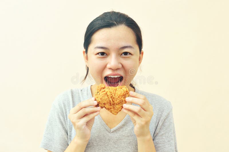 Tenencia feliz de la mujer y consumición del pollo de las fritadas fotos de archivo