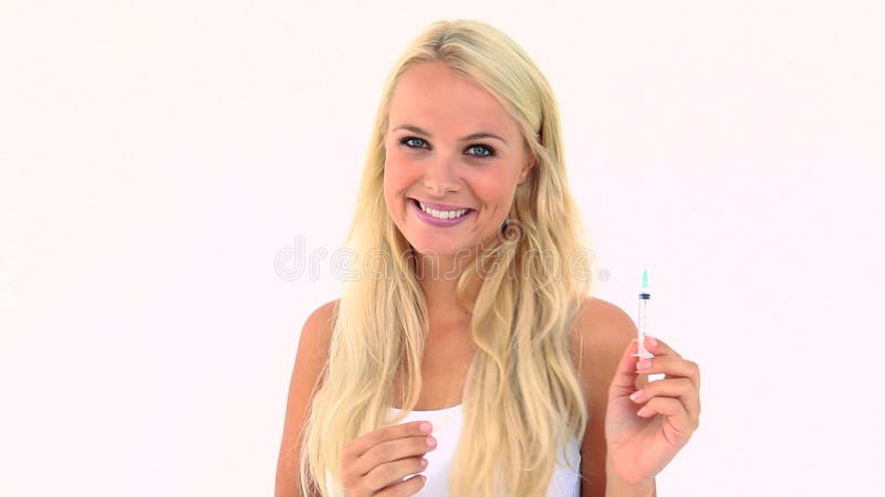 Tenencia rubia sonriente una jeringuilla almacen de video