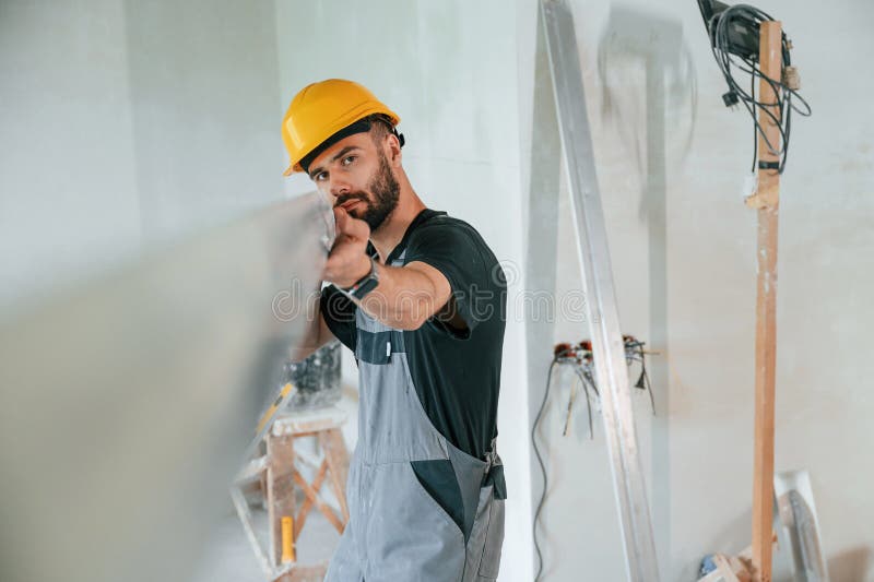 Tenere a mano materiale da costruzione. l'uomo sta riparando nell'appartamento immagini stock
