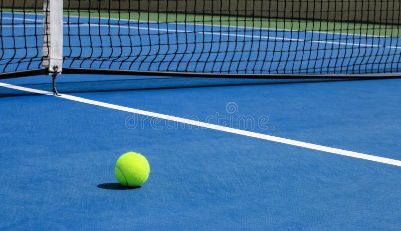 Tennis Ball on Blue Court with Net in Background