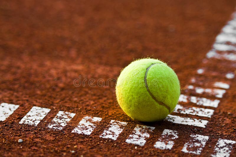 Foto di una palla da tennis sul campo durante il tramonto.