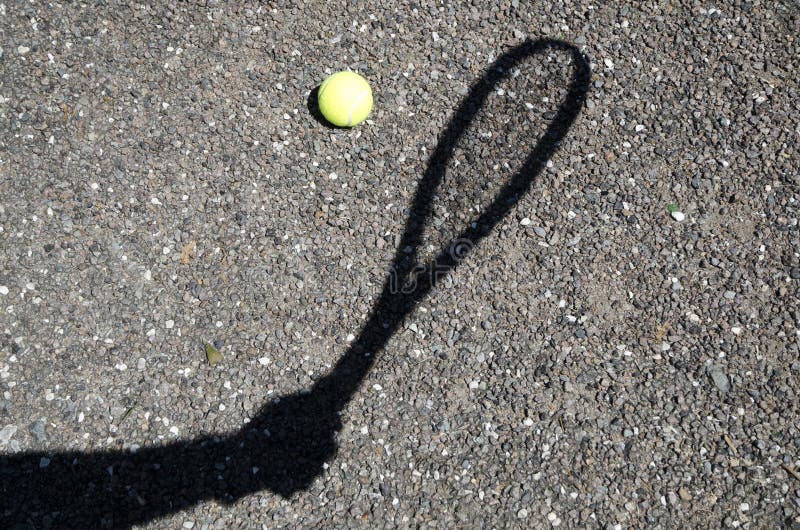 Tennis ball on the ground with a racket shadow under the sunlight stock photo Tennis ball on the ground with a racket shadow under the sunlight stock photo