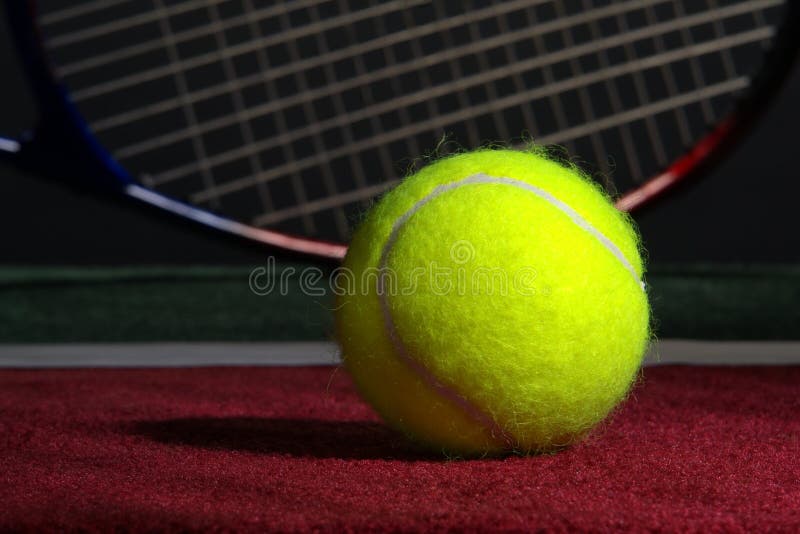 Tennis ball and racket on soft indoor court surface. Tennis ball and racket on soft indoor court surface