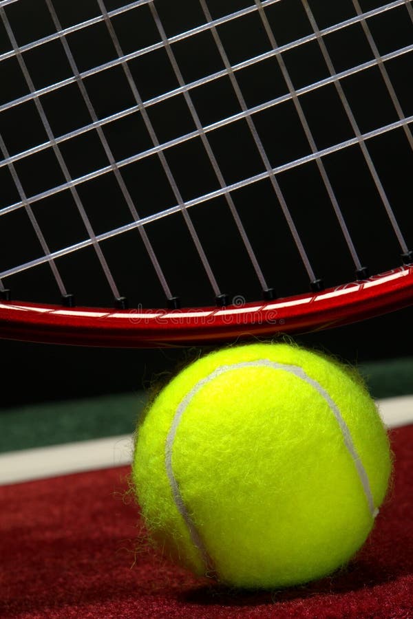 Yellow tennis ball and fiberglass racket on a soft surface indoor court. Yellow tennis ball and fiberglass racket on a soft surface indoor court