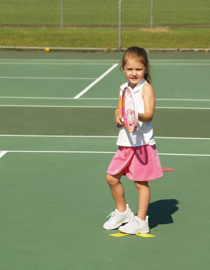 Giovane ragazza in possesso di una racchetta da tennis, mentre in piedi su un campo da tennis per lezioni.