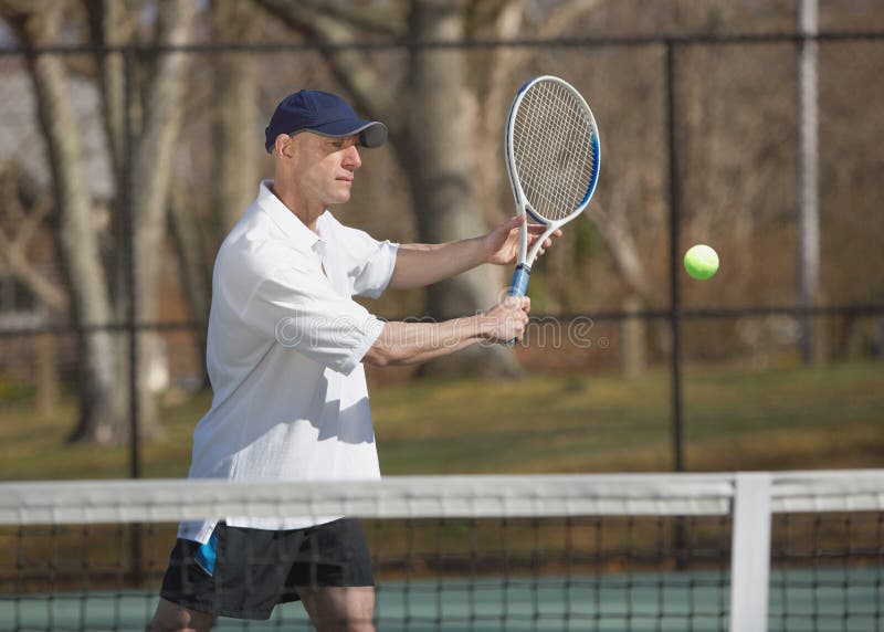 Handsome man tennis player at court hitting ball