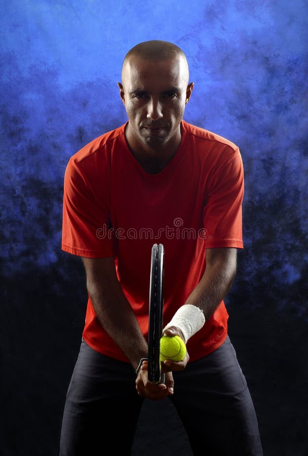 A portrait of a tanned sportive tennis player with a racket against blue and black background. tennis player portrait.