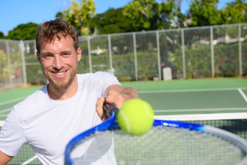 Tennis player portrait man showing ball and racket. Smiling happy male athlete inviting you to play tennis. Healthy active sport and fitness lifestyle concept.