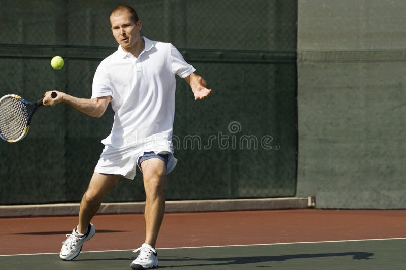 Tennis Player swinging tennis racket in forehand motion on tennis court