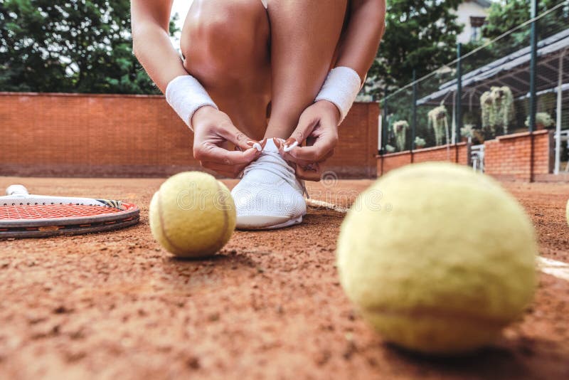 Close up view of Tennis player tying shoelaces in tennis court. Young woman on tennis court in the sport club, active, adult, athlete, athletic, attractive, ball, balls, beautiful, beauty, body, clay, closeup, clothing, fashion, female, fitness, game, girl, healthy, hobby, holding, legs, leisure, lifestyle, match, model, net, outdoor, people, person, professional, racket, racquet, sexy, shoes, sit, skirt, sneakers, sportive, sporty, stylish, training