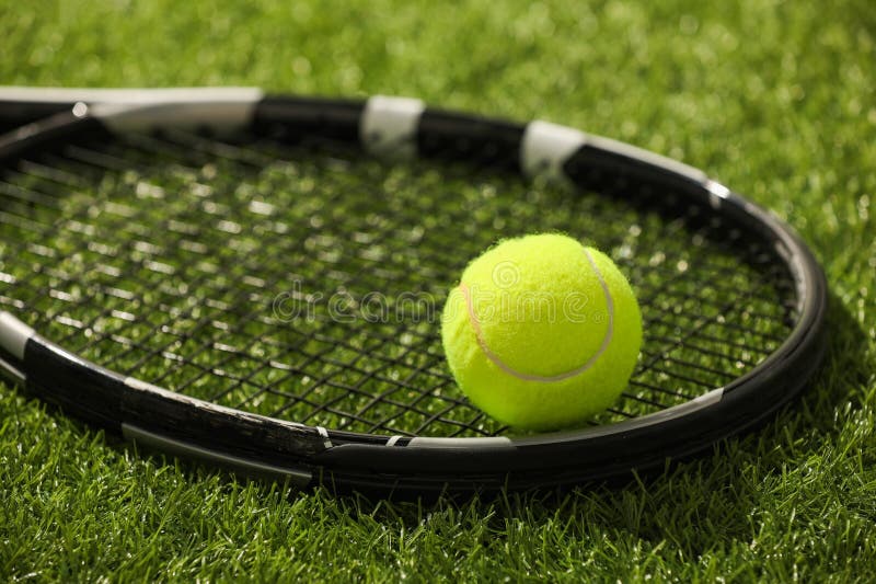 Tennis racket and ball on green artificial grass, closeup royalty free stock images