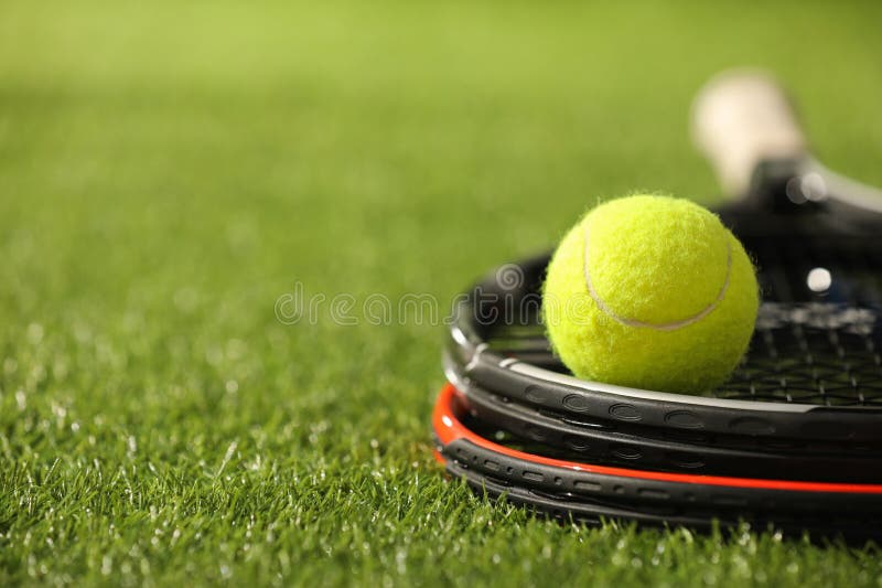 Tennis rackets and ball on green artificial grass, closeup. Space for text royalty free stock image
