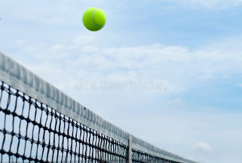 Tennisboll som netto flyger över domstolen för mitt på blå himmel för bakgrund fotografering för bildbyråer Tennisboll som netto flyger över domstolen för mitt på blå himmel för bakgrund fotografering för bildbyråer