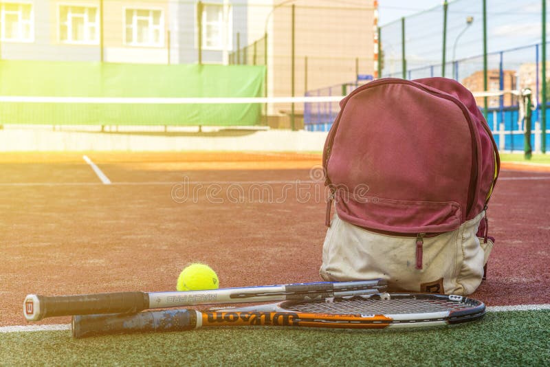 Tennisracket med en boll nära sporten hänger löst med utrustning på domstolen på sommardag arkivfoto Tennisracket med en boll nära sporten hänger löst med utrustning på domstolen på sommardag arkivfoto