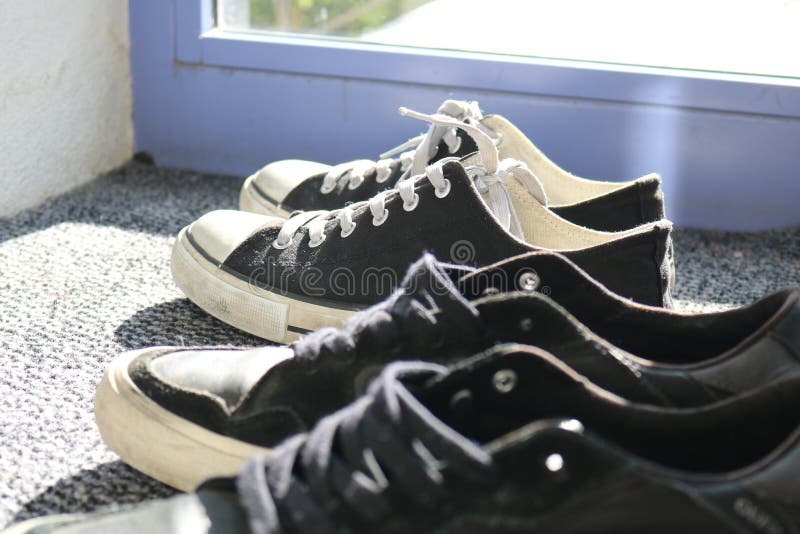 Tennisschoenenschoenen op een tapijt dichtbij huisingang stock afbeeldingen Tennisschoenenschoenen op een tapijt dichtbij huisingang stock afbeeldingen