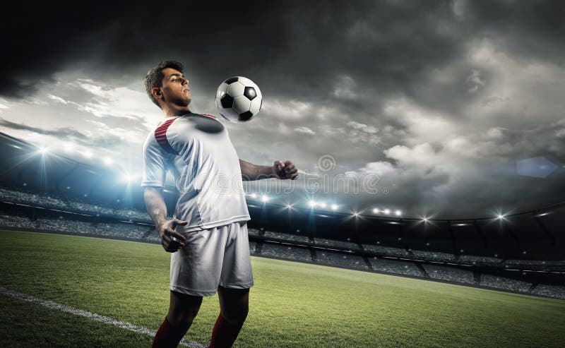Tenue de joueur de football une boule avec son coffre dans le stade photos stock Tenue de joueur de football une boule avec son coffre dans le stade photos stock