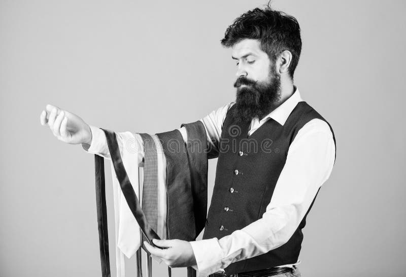 Tenuta barbuta dei pantaloni a vita bassa dell'uomo poche cravatte Tipo con la barba che sceglie cravatta Cravatta perfetta Legam immagini stock Tenuta barbuta dei pantaloni a vita bassa dell'uomo poche cravatte Tipo con la barba che sceglie cravatta Cravatta perfetta Legam immagini stock