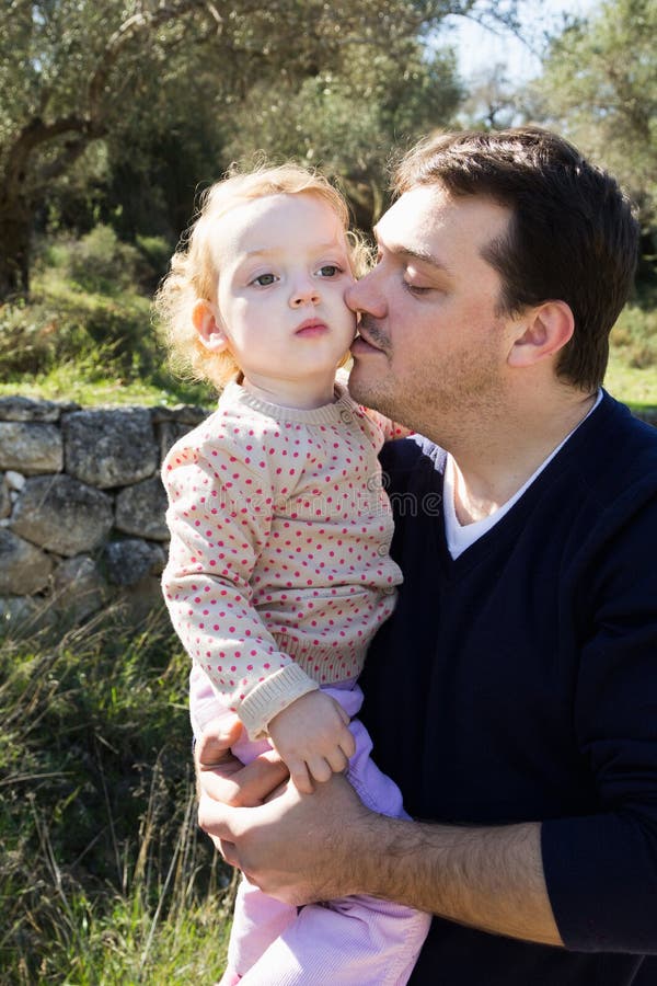Tenuta felice del padre sulla piccola figlia delle mani fotografia stock Tenuta felice del padre sulla piccola figlia delle mani fotografia stock