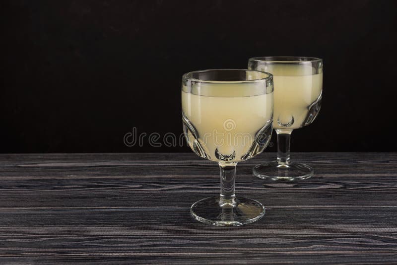 Tepache - traditional Mexican fermented drink from pineapple. Homemade kvass in drinking glasses on wooden table. Dark background