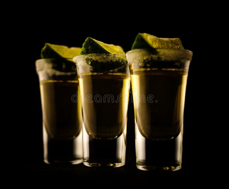 Tequila messicana dell'oro con calce e sale sulla tavola di legno fotografia stock libera da diritti Tequila messicana dell'oro con calce e sale sulla tavola di legno fotografia stock libera da diritti