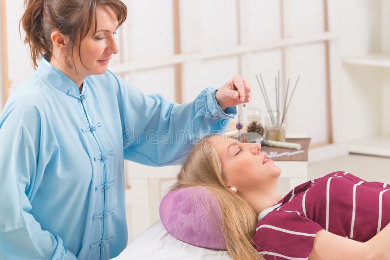 Terapeuta que usa o pêndulo fotografia de stock Terapeuta que usa o pêndulo fotografia de stock
