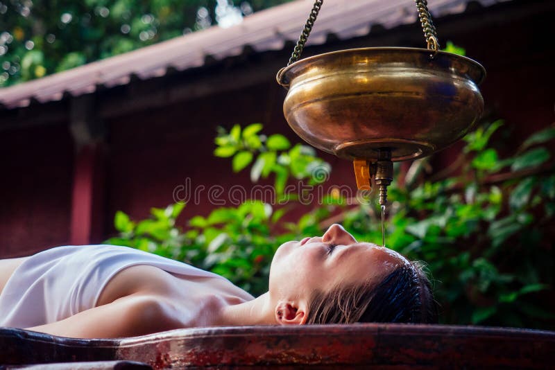 Terapia di cura alternativa per massaggi Ayurveda bella femmina caucasica con trattamento di shirodhara steso su un legno