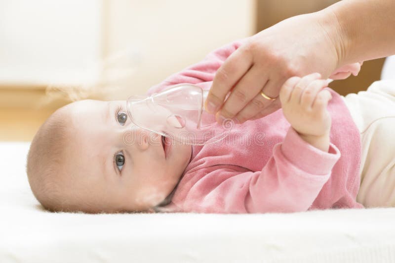 Baby taking respiratory therapy. Hand holding the mask of a nebuliser. Baby taking respiratory therapy. Hand holding the mask of a nebuliser.