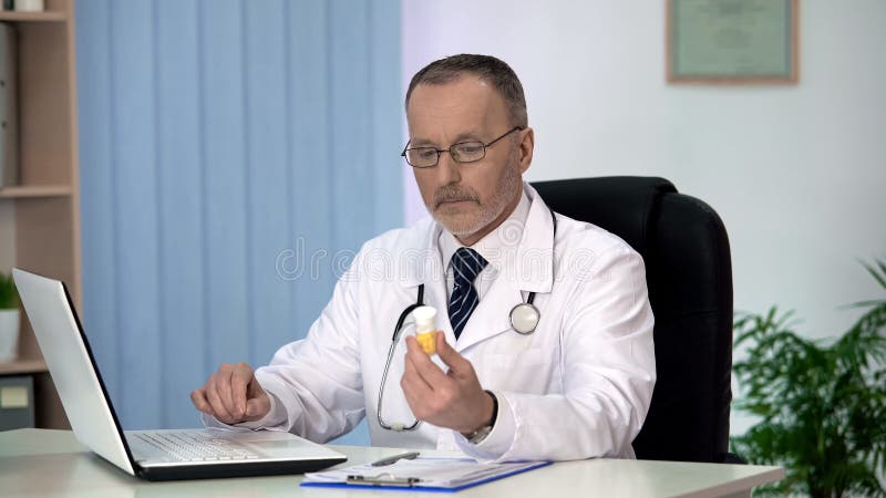 Terapista che cerca le medicine in catalogo online sul computer portatile, prescribtion fotografie stock Terapista che cerca le medicine in catalogo online sul computer portatile, prescribtion fotografie stock