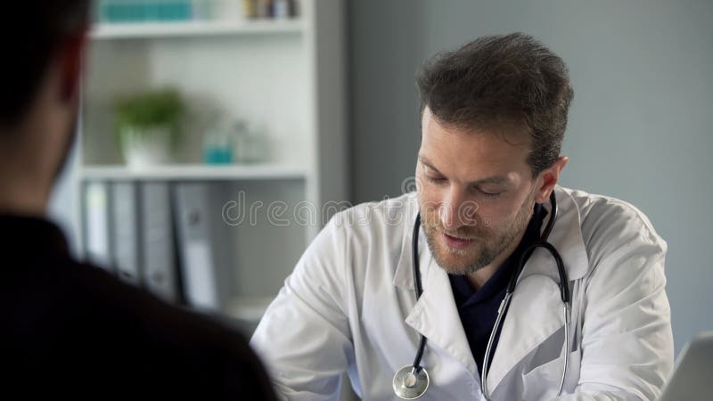 Terapista maschio che chiacchiera con il paziente che fa le note, sanità e medicina fotografia stock libera da diritti Terapista maschio che chiacchiera con il paziente che fa le note, sanità e medicina fotografia stock libera da diritti